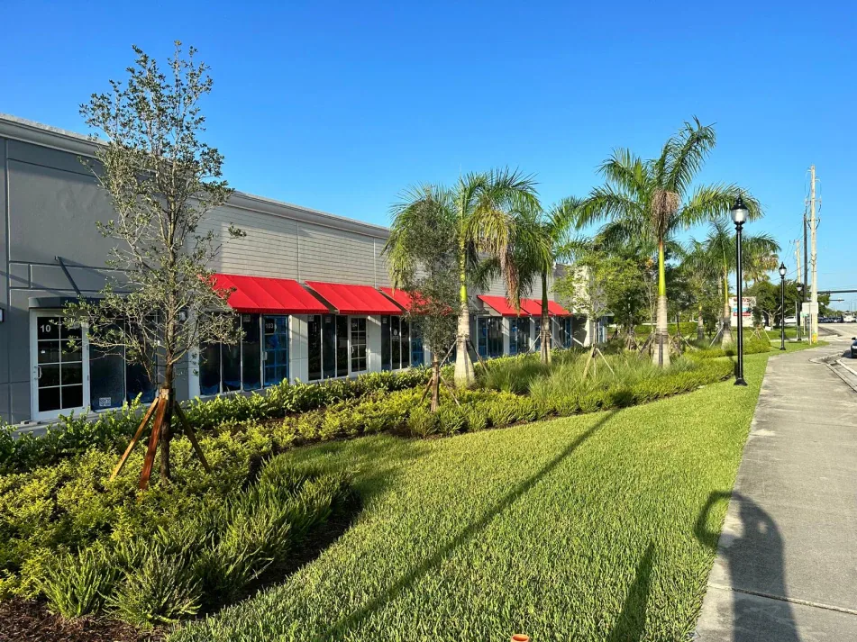 Retail strip with red awnings, royal palms, and manicured landscaping in Miami, FL